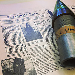 One of Merle A. Tuve's "personal" proximity fuzes is displayed next to a news clipping detailing how the fuze was made. 