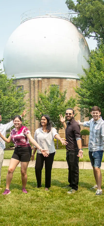 Interns cheer in front of the Atomic Physics Observatory