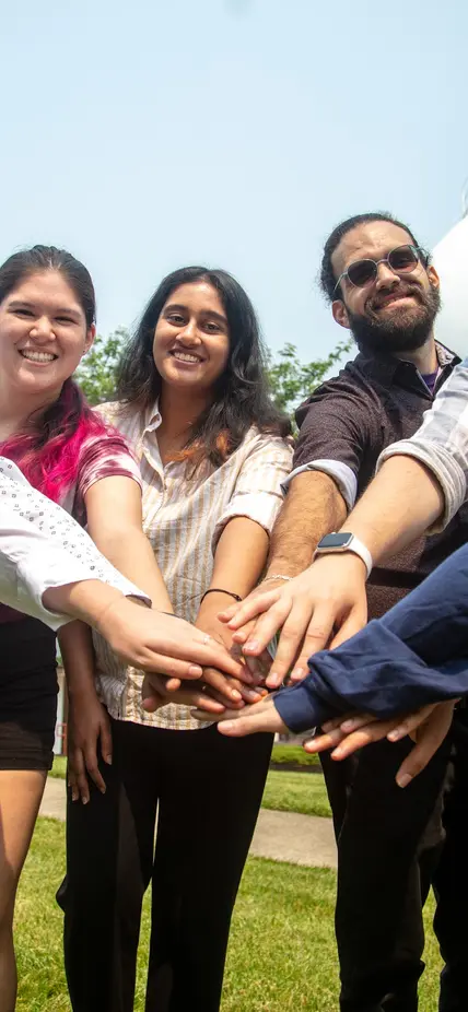 The 2023 summer interns hold their hands in the middle of the circle