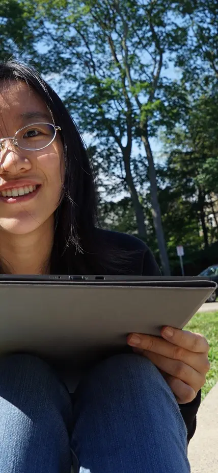 Meng Gu sits outside with a laptop