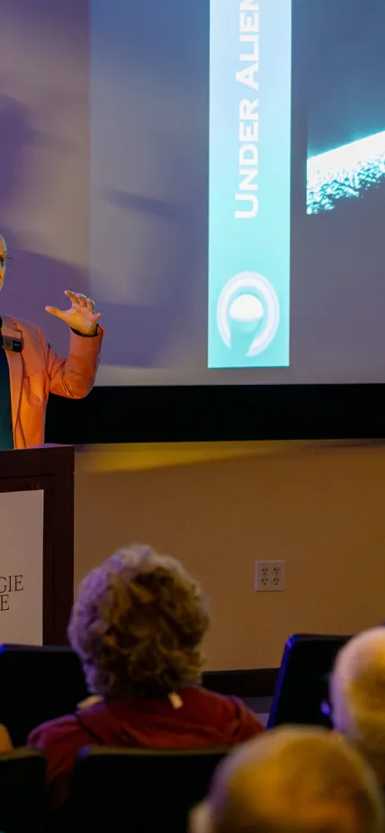 Phil Plait holds his hands up illustrating the pressures that led to Enceladus' fissues