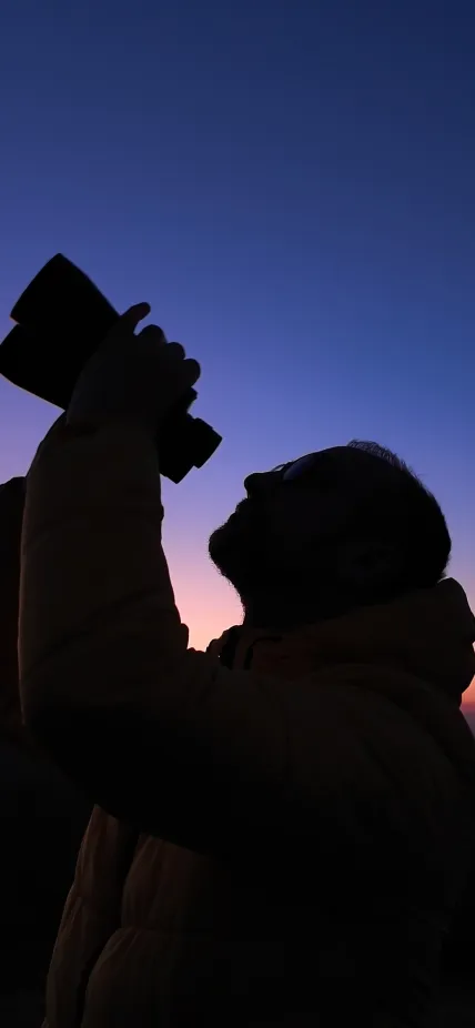 amateur astronomer looks at the sky with binoculars