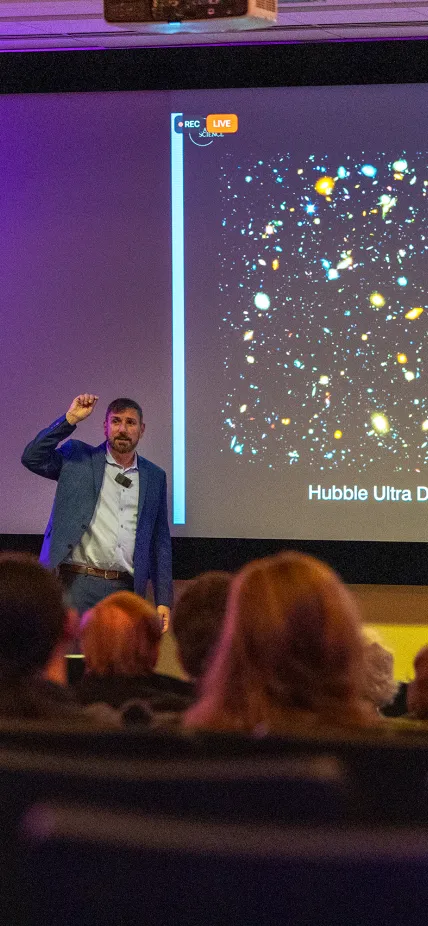 John Mulchaey stands in front of screen with JWST image