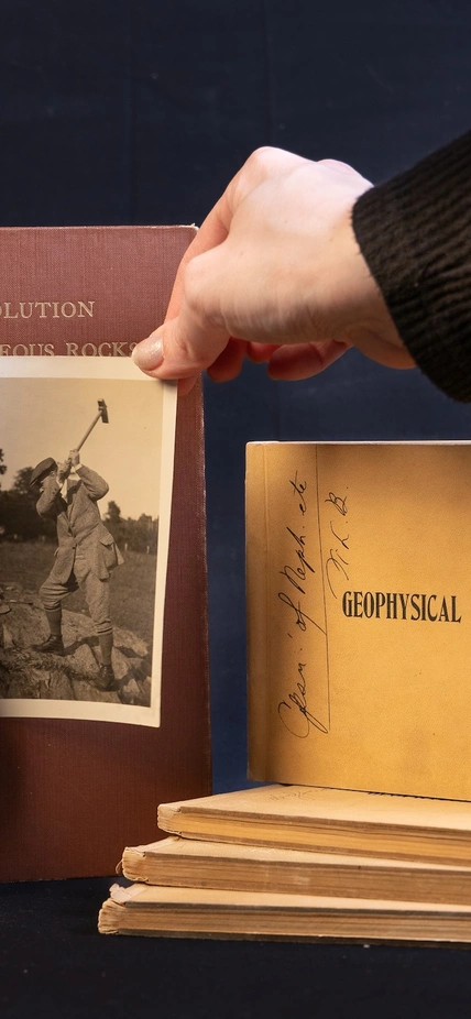 A hand places a photo onto a still life style photoshoot of the Bowen Journals
