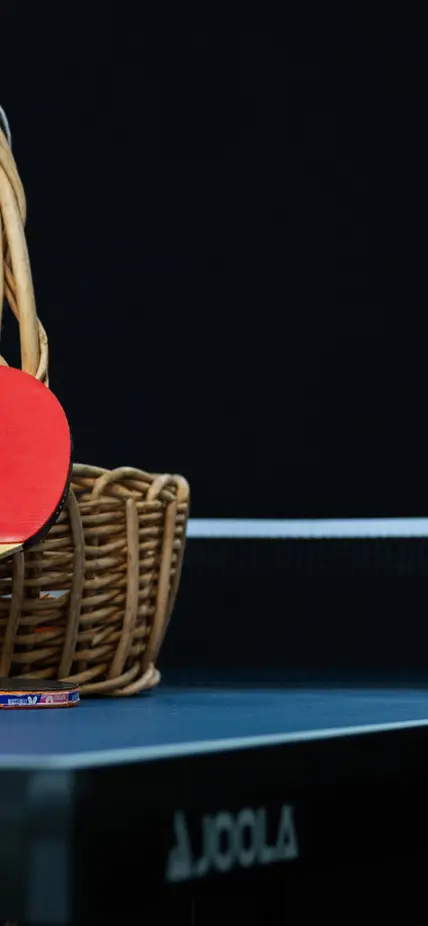 The ping pong table on a black background with a basket of supplies sitting on top. 