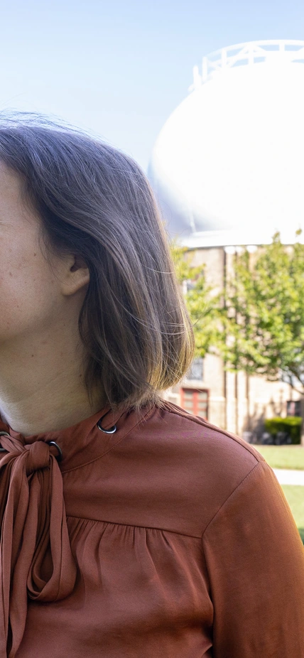 Marion Le Voyer looks to the left in front of the Atomic Physics Observatory