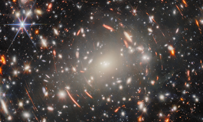 JWST picture of the mega-monster that is galaxy cluster Abell S1063. This dense collection of heavy galaxies is surrounded by glowing streaks of light, and these warped arcs are the true object of scientists’ interest: faint galaxies from the universe’s distant past. ESA/Webb, NASA & CSA, H. Atek, M. Zamani (ESA/Webb) Acknowledgement: R. Endsley