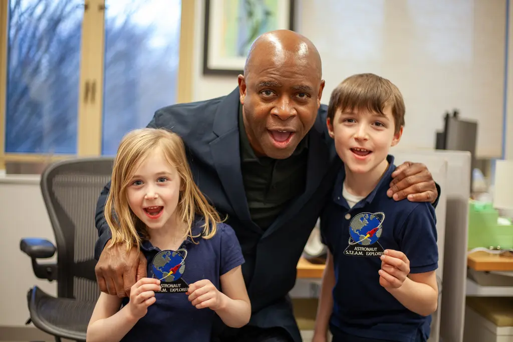 Two enthusiastic space fans pose with former astronaut and current NASA educator Leland Melvin