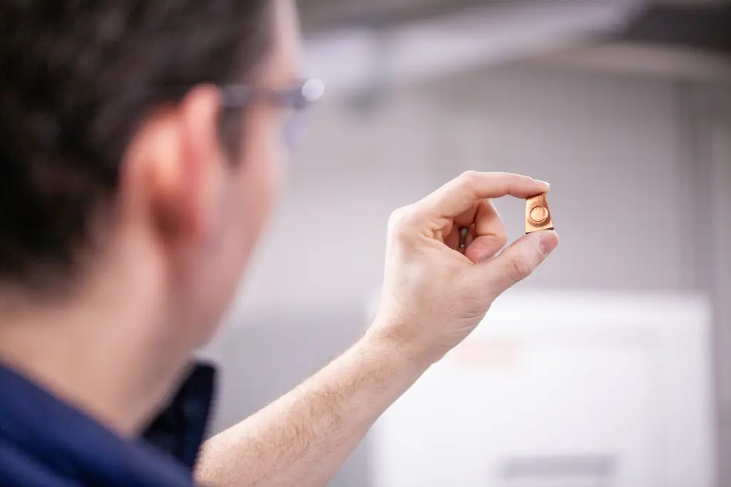 Javier holds up the copper sample to show the ring of deformation from the press. 