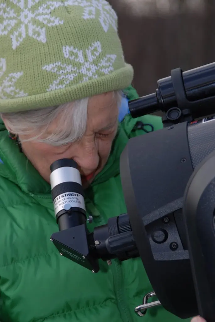 Maxine Singer looks through a telescope during an outreach activity. 