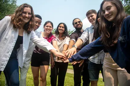 A group of interns puts their hands together. 