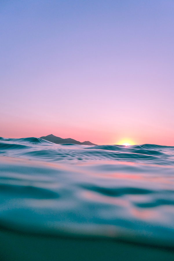 The Sun peeks over the horizon of the ocean, viewed from an in-water perspective. 