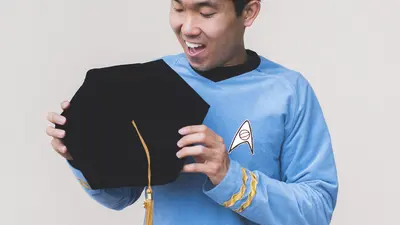 Mike Wong holds his PhD graduation cap in a Star Trek uniform
