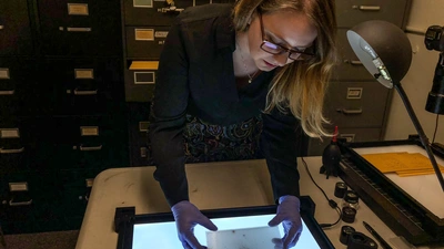 Kit Whitten holding a plate from the Sandage colelction