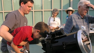 A young Open House attendee looks through a telescope