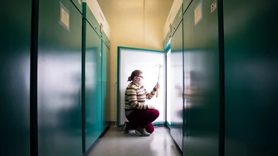 Brittany Belin kneels in front of a plant growth chamber