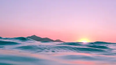 The Sun peeks over the horizon of the ocean, viewed from an in-water perspective. 