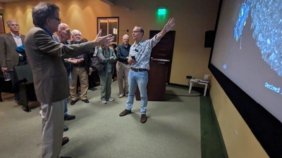 Conel holds his hand up toward a meteorite sample during a discussion with neighborhood guests at the end of his Neighborhood Lecture