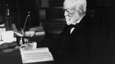 Andrew Carnegie seated at a desk with a book, circa 1913 1913