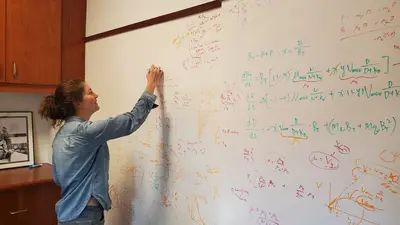 Emily Zakem writes on the whiteboard wall of a Carnegie Science office at Caltech. 