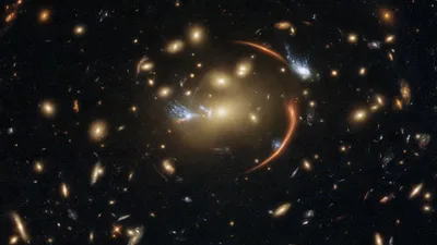 This Hubble image shows the galaxy cluster MACS J0138.0-2155, which is so massive that its gravity bent and magnified light streaming not only from an extremely distant background galaxy but also from a supernova event in this galaxy. The color image was made using observations from eight different filters spread across Hubble’s Advanced Camera for Surveys (ACS) and Wide Field Camera 3 (WFC3). The color results from assigning different hues to each monochromatic image associated with an individual filter. I