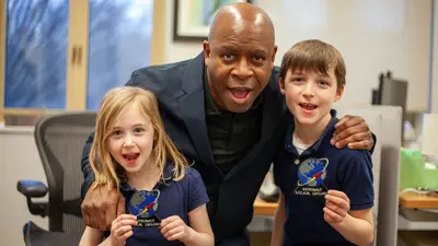 Two enthusiastic space fans pose with former astronaut and current NASA educator Leland Melvin