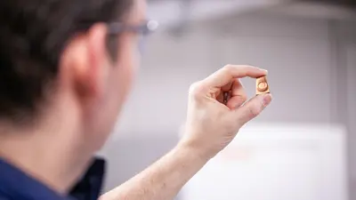 Javier holds up the copper sample to show the ring of deformation from the press. 