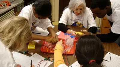 Maxine Singer works with STEM students as part of the First Light program she founded