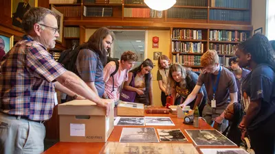 Interns lean over historic materials at the Earth and Planet Laboratory Laboratory 