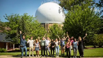 Interns pose for a group photo infront of the Atomic Physics Observatory. 