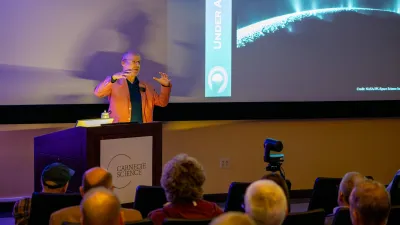 Phil Plait holds his hands up illustrating the pressures that led to Enceladus' fissues