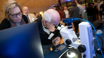 Carolyn and David Gambrel look through a microscope at a Donor Appreciation Event held after a Capital Science Evening lecture by Dr. Margaret McFall-Ngai