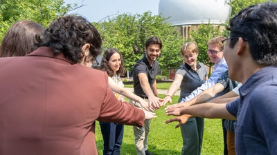 Interns hold hands in before cheering "Science!" 