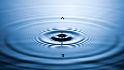 Water droplet ripples outward in blue water