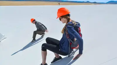 Allison Matthews slides down the side of one of the antennae in the Very Large Array.