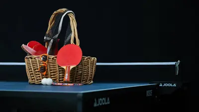 The ping pong table on a black background with a basket of supplies sitting on top. 