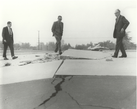 Charles Richter (right) and others viewing buckled pavement.