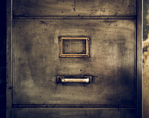 the front of an old file cabinet without a paper label in the metal frame