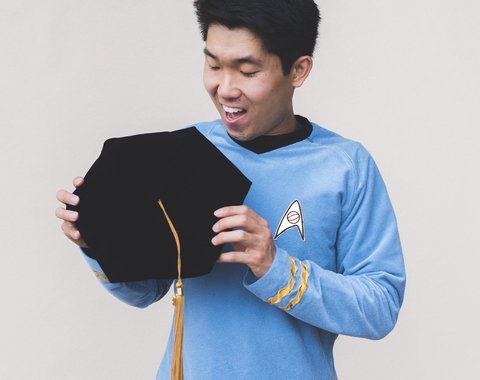 Mike Wong holds his PhD graduation cap in a Star Trek uniform