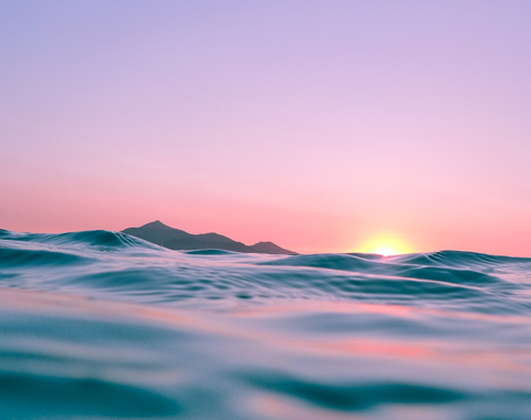 The Sun peeks over the horizon of the ocean, viewed from an in-water perspective. 