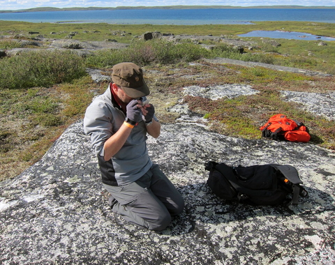 Graham Pearson using on of the field geologist's main tools, a simple hand lens, to look at the mineralogy of a rock during fieldwork at the Slave Craton, Canada.