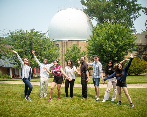 Interns cheer in front of the Atomic Physics Observatory