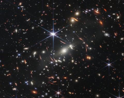 JWST Image of a foreground cluster gravitationally lensing background galaxies.