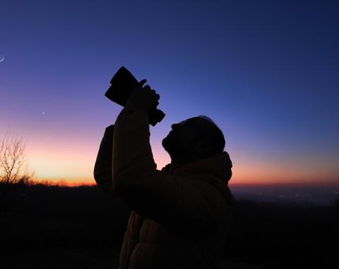 amateur astronomer looks at the sky with binoculars