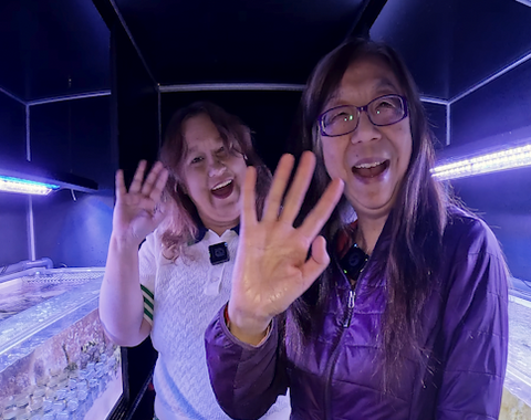 Natasha & Yixian wave at the camera after discussing coral symbiosis