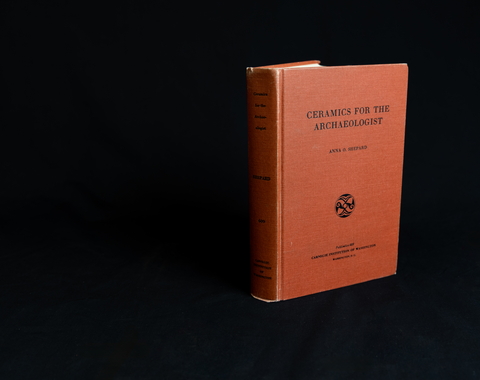 Red book on black backdrop. "Ceramics for the archaeologist"