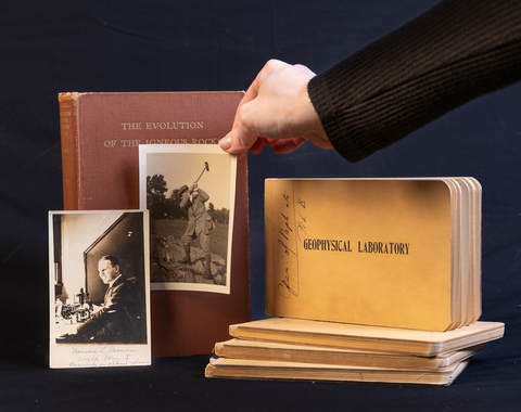 A hand places a photo onto a still life style photoshoot of the Bowen Journals