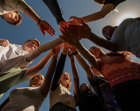 Go team on three! Looking up at interns with hands in during an early internship huddle. 
