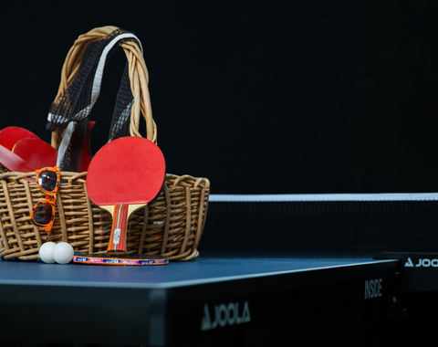 The ping pong table on a black background with a basket of supplies sitting on top. 