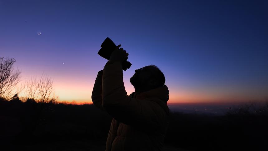 amateur astronomer looks at the sky with binoculars